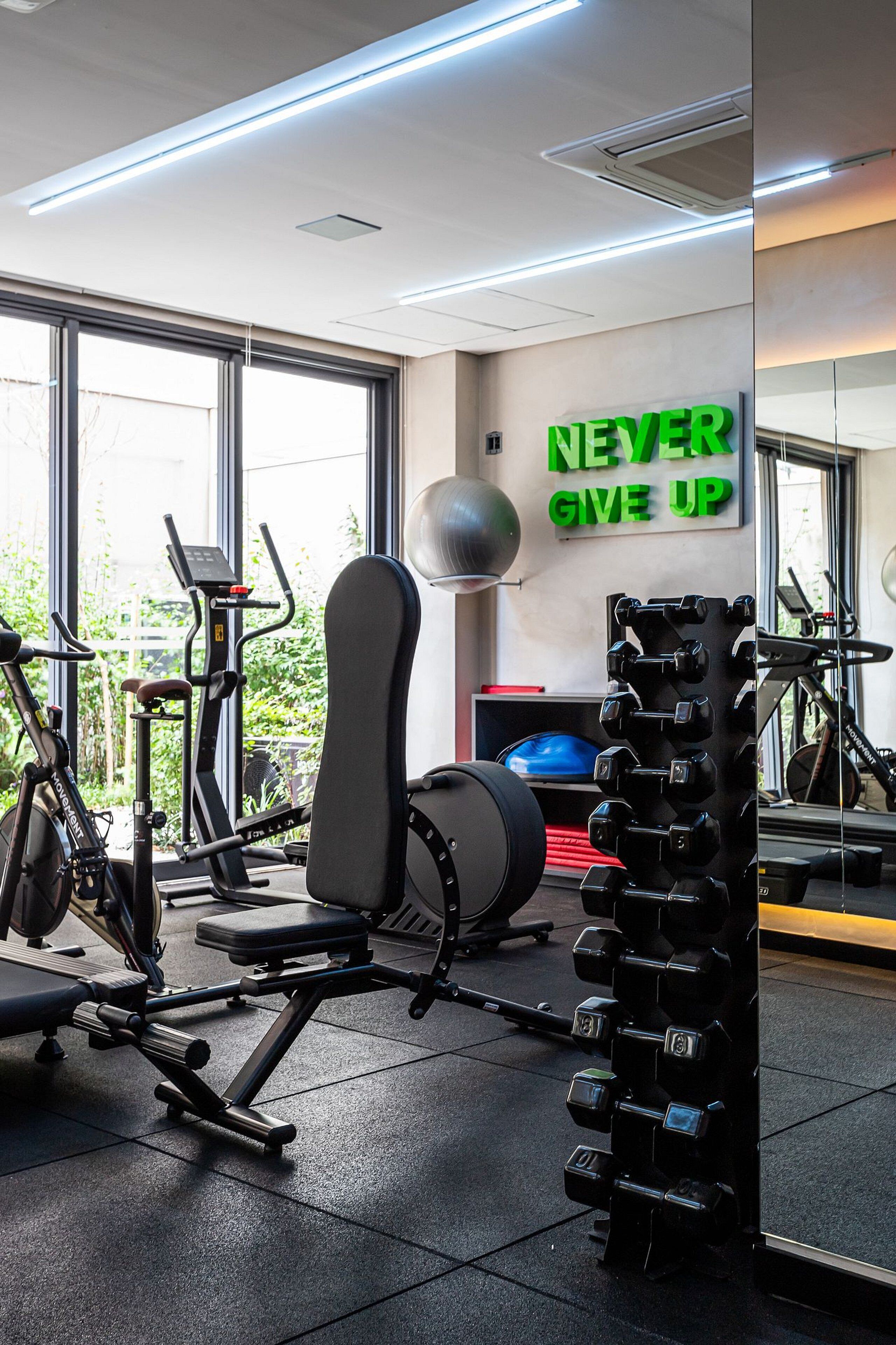 A gym with exercise equipment, a bench, and a motivational sign.