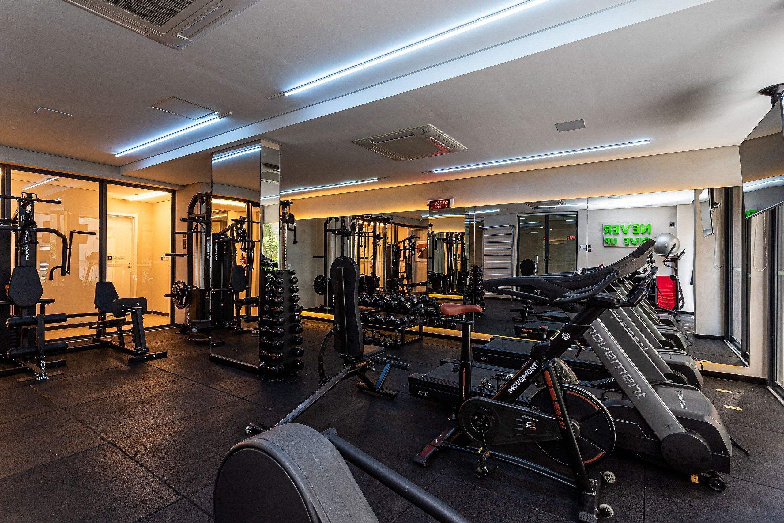 Un gimnasio con equipo de ejercicio, una cinta de correr y un espejo.
