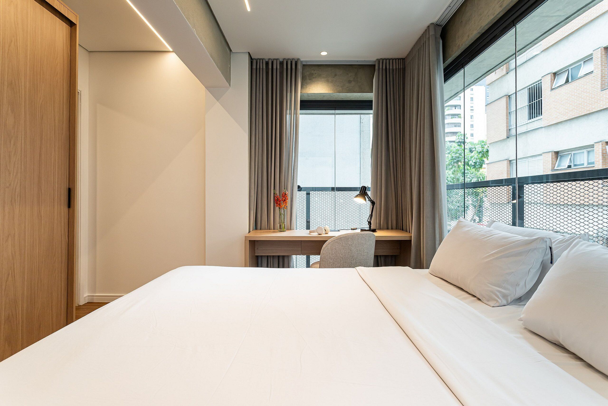 Une chambre d’hôtel avec un lit, un bureau et une fenêtre avec des rideaux.