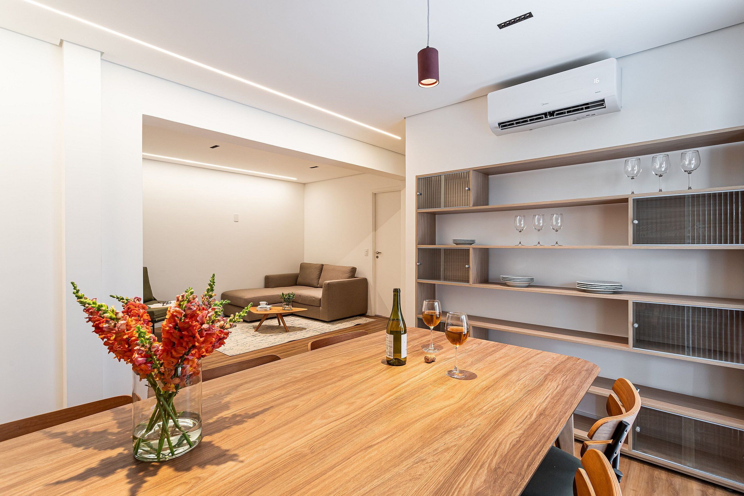 Ein modernes Wohnzimmer mit einem Holzesstisch, einer Blumenvase und einem Sofa.