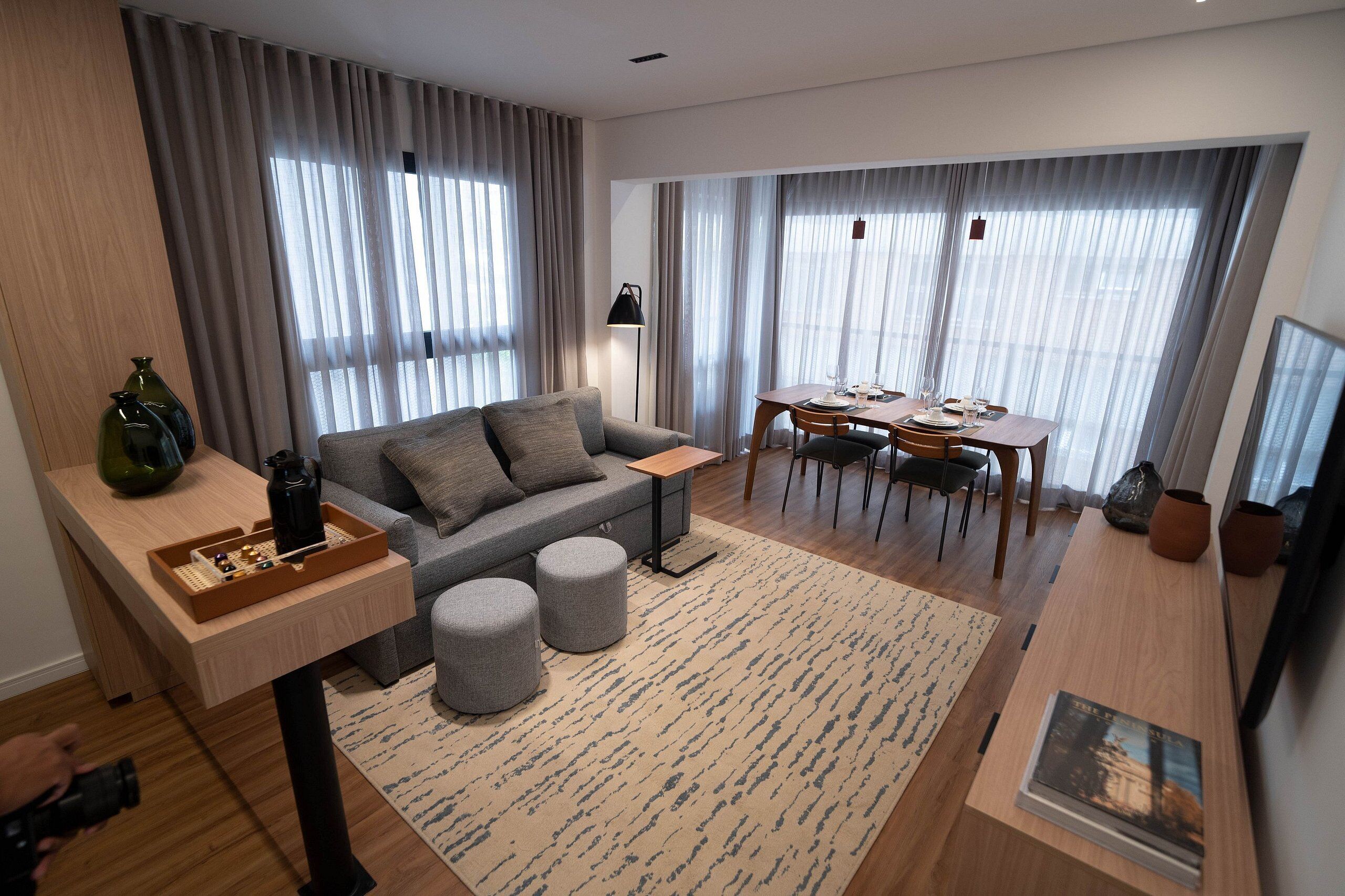 A modern living room with a sofa, ottomans, a dining table, and a coffee table.