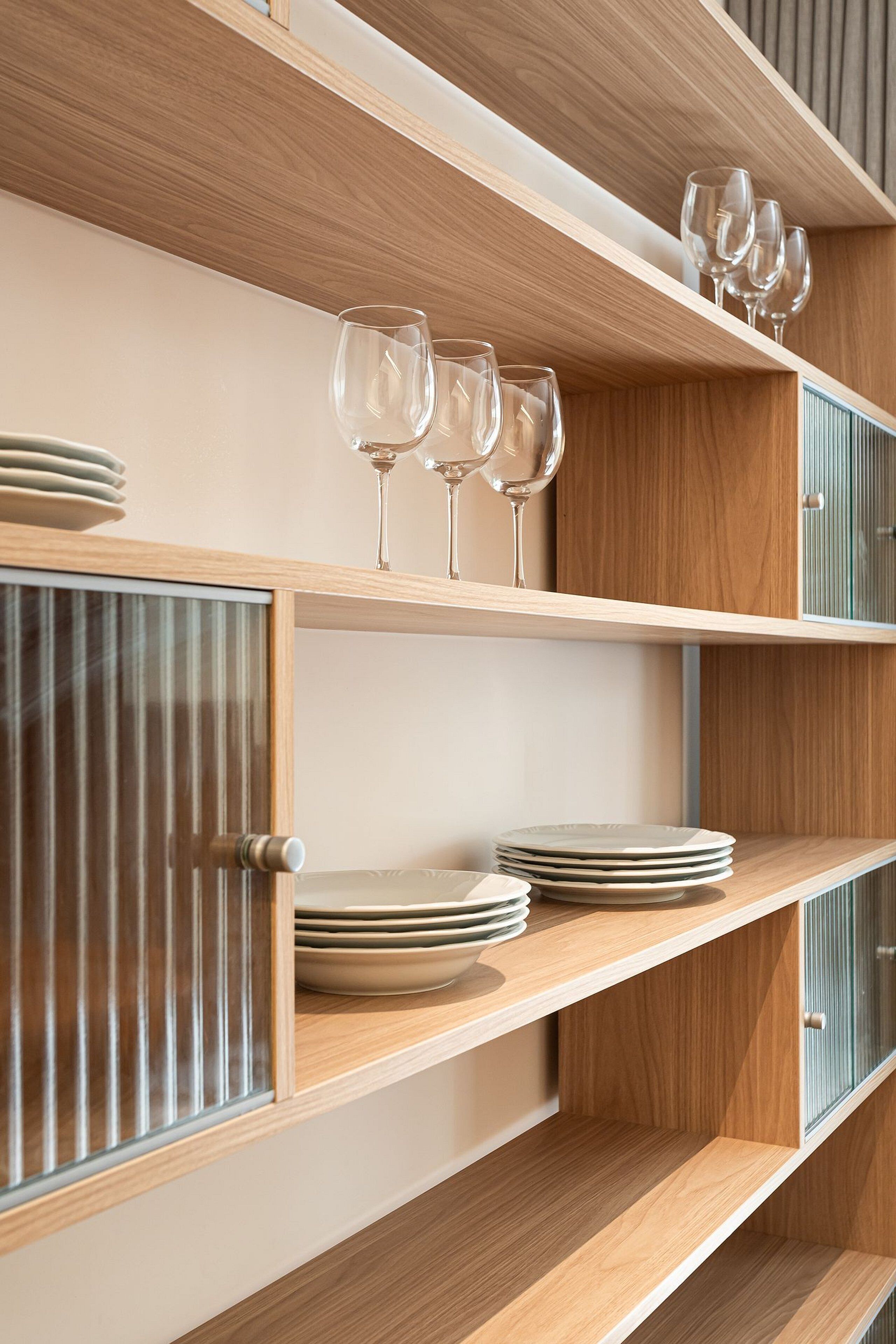 A wooden shelf unit with glassware and plates.