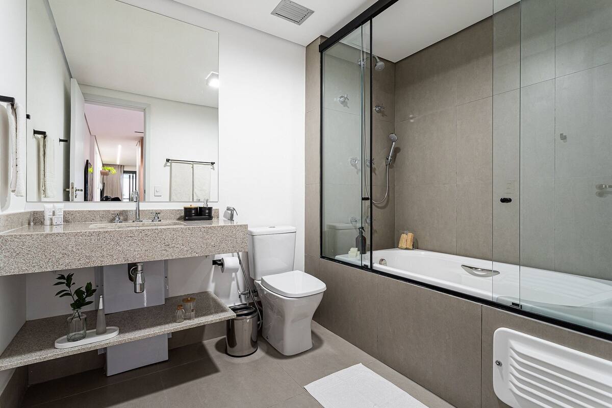 A modern bathroom with a glass-enclosed shower, a white toilet, and a granite countertop.