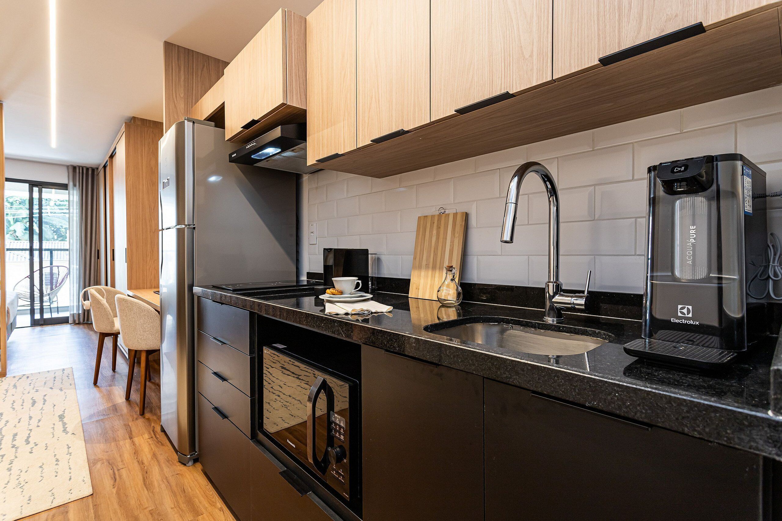 A modern kitchen with a built-in oven, a coffee maker, and a wooden cutting board.