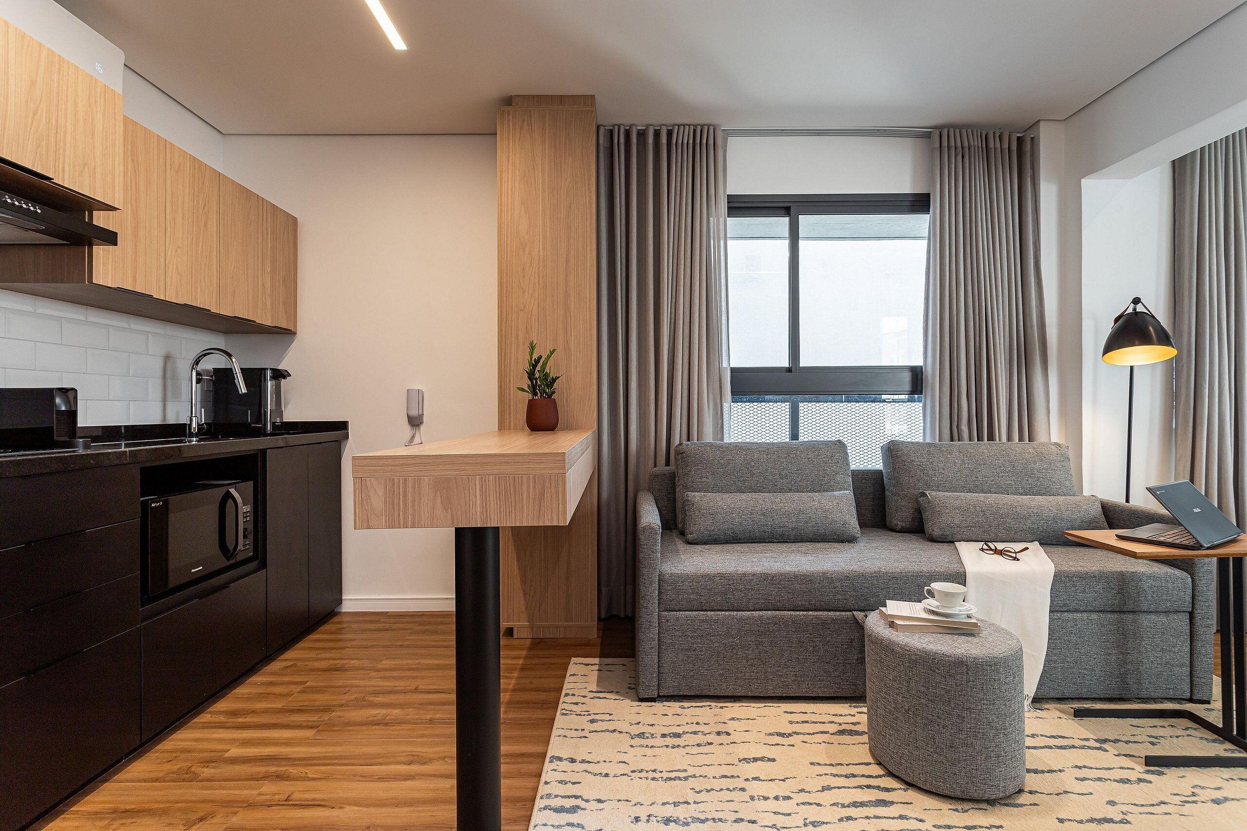 A modern kitchen with dark cabinetry, a built-in oven, and a coffee machine.