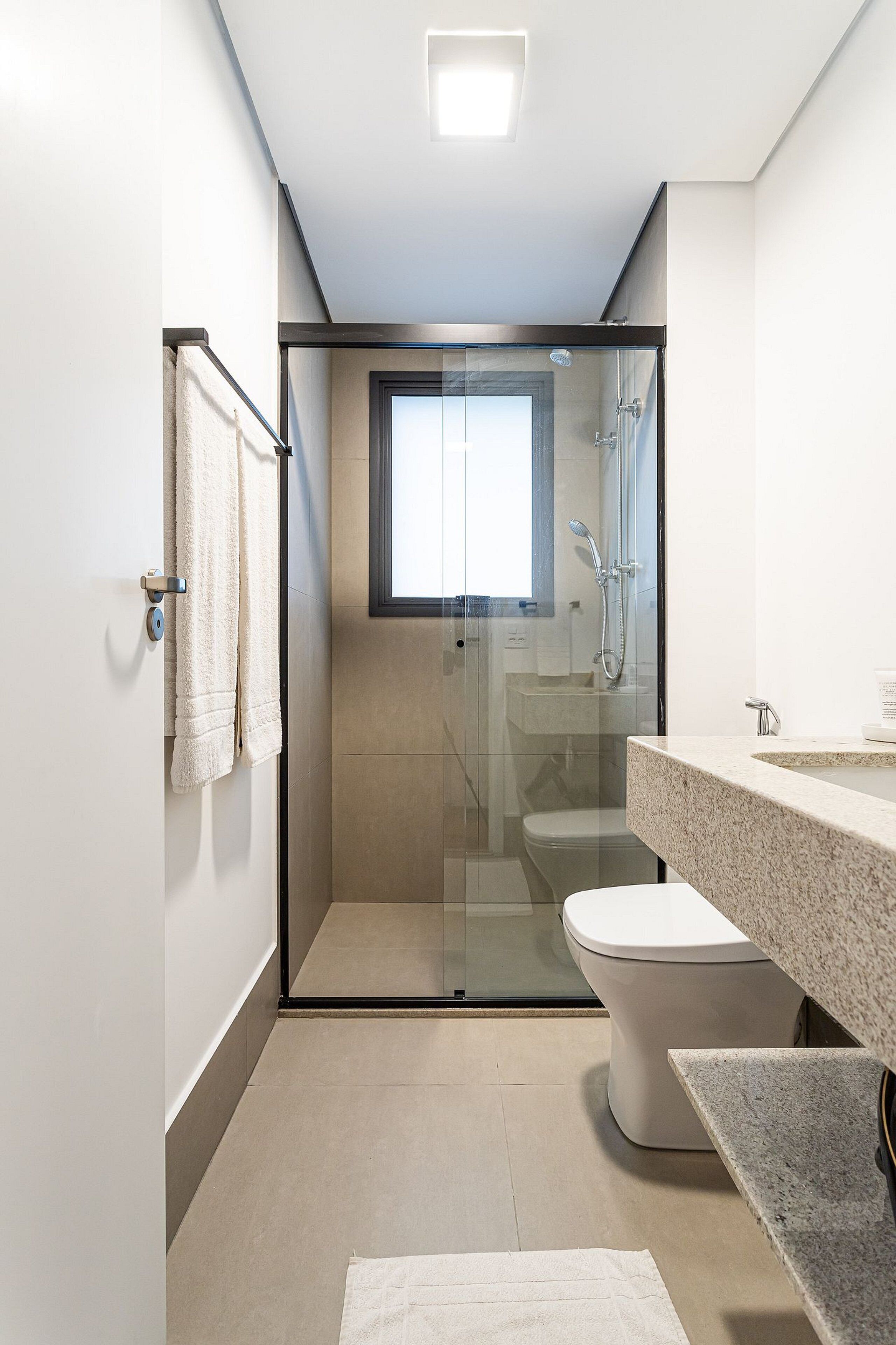Une salle de bain moderne dotée d’une douche à parois de verre, de toilettes et d’un lavabo avec un plan de travail en granit.