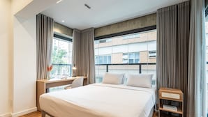A modern hotel room with a large bed, a desk, and a view of a building through the window. -  Pivô Alameda Franca by Viva - Conforto e Estilo nos Jardins (São Paulo)