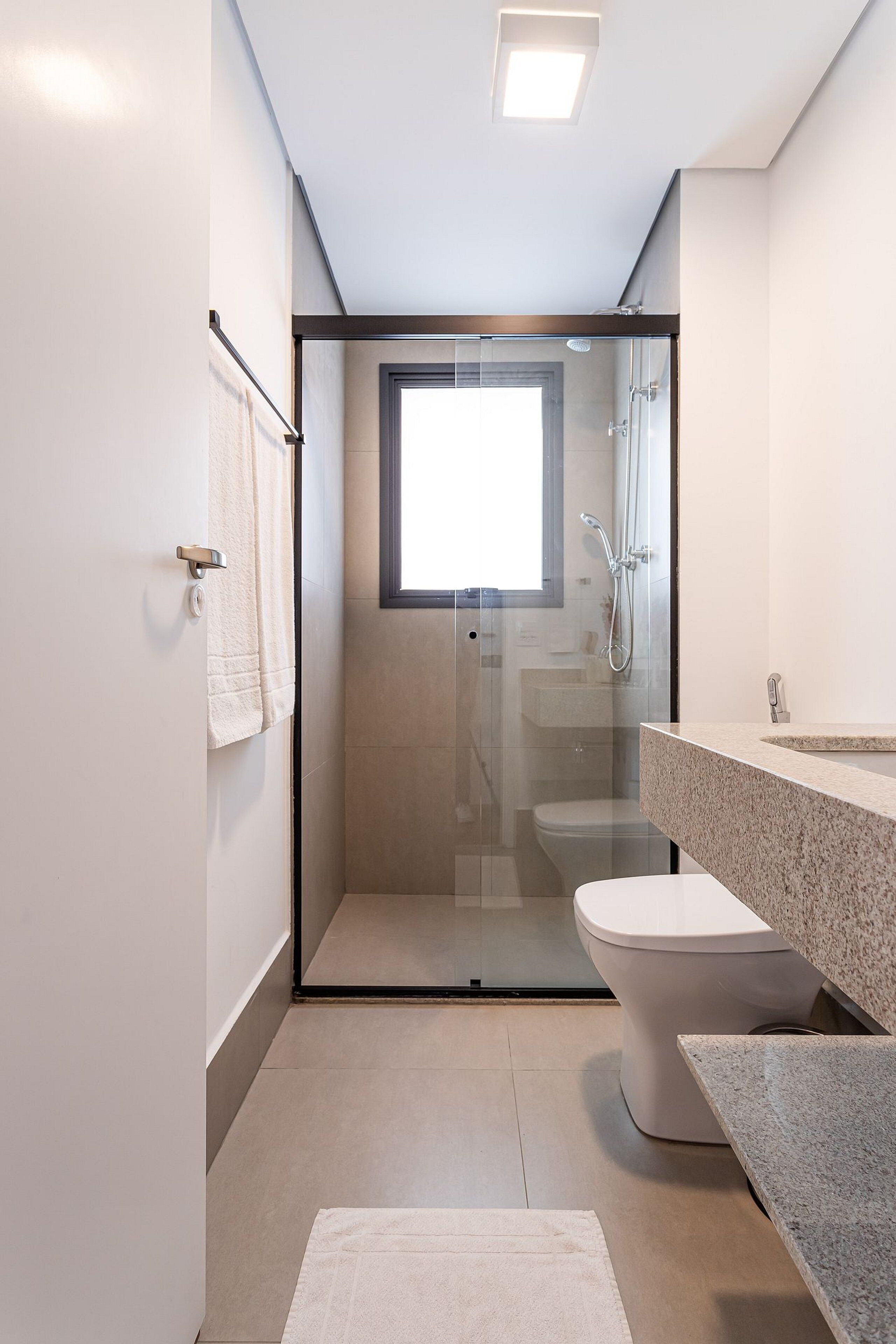 Une salle de bain moderne dotée d’une douche à parois de verre, de toilettes et d’un lavabo avec un plan de travail en granit.