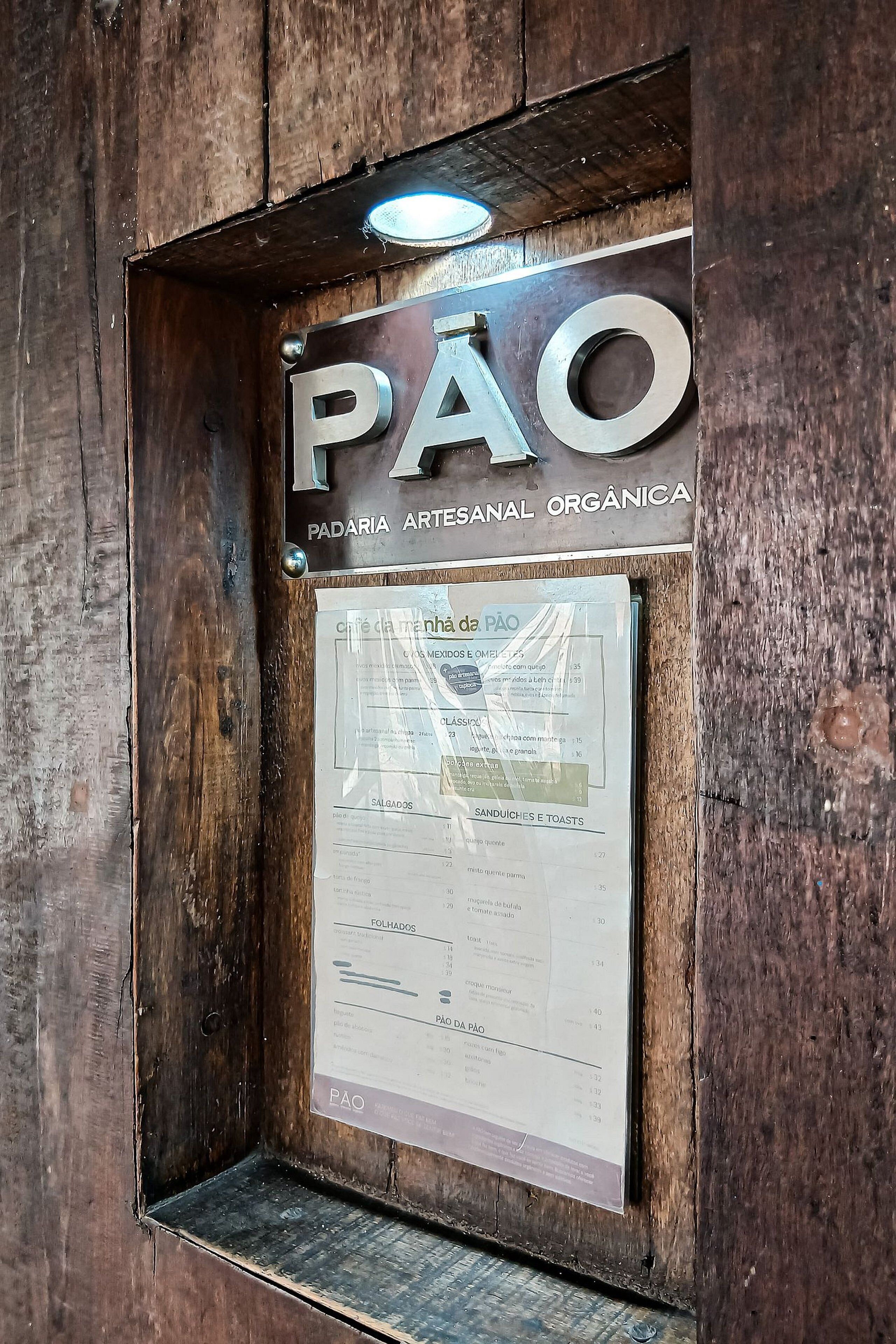 Une porte en bois avec une enseigne indiquant « PAO » et un menu.