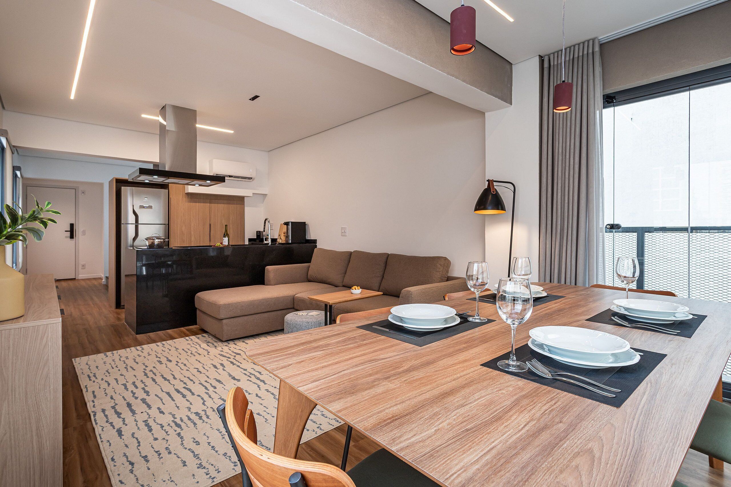 A modern living space with a dining area, kitchen, and a large window.