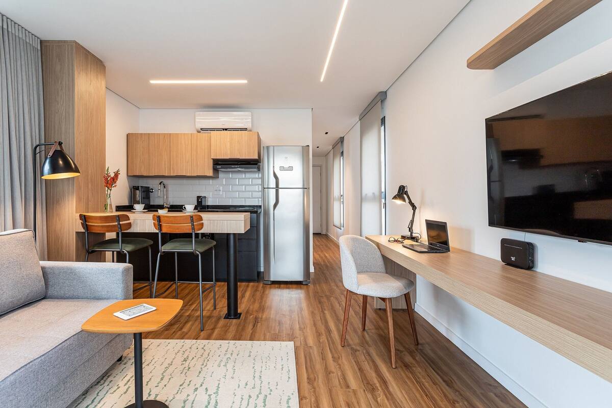 A modern kitchen with wooden cabinets, a refrigerator, and a dining area with chairs and a table.