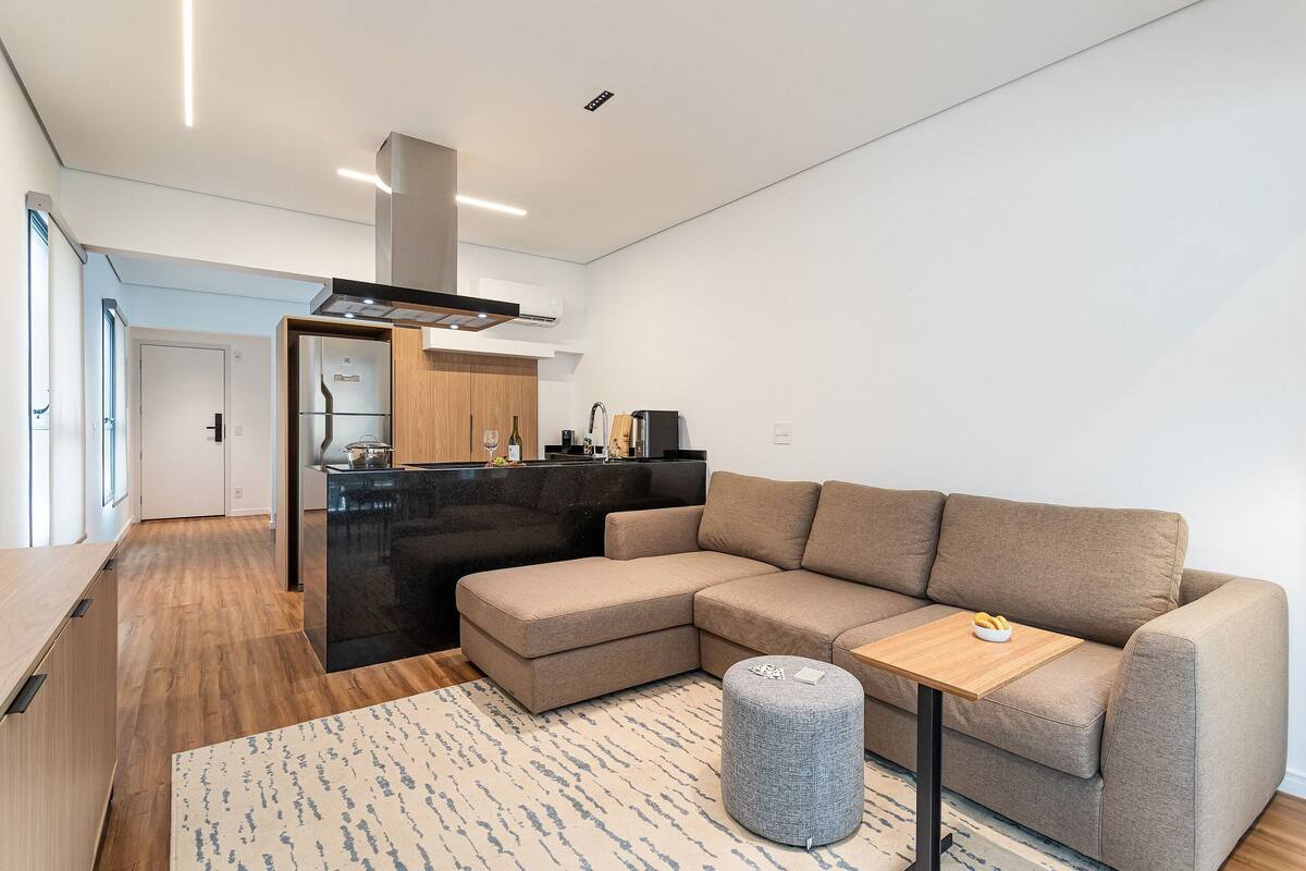 A modern living room with a sectional sofa, a small wooden table, and a round ottoman.