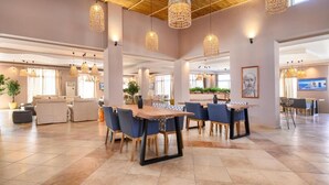 A spacious dining area with a large wooden table and blue chairs, surrounded by hanging woven light fixtures. - Aegean Bay Hotel - All Inclusive (Marmari)