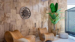 A room with a wooden wall, a large potted plant, and two woven chairs. - Aegean Bay Hotel - All Inclusive (Marmari)