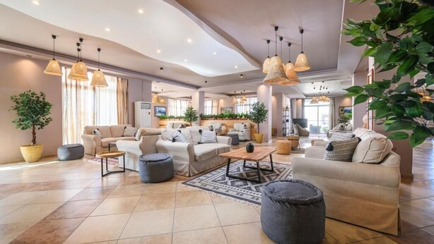 A spacious living area with multiple sofas, a coffee table, and hanging wicker lamps. - Aegean Bay Hotel - All Inclusive (Marmari)
