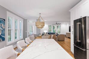 Et moderne køkken med en stor ø, hvide skabe og et sort køleskab.