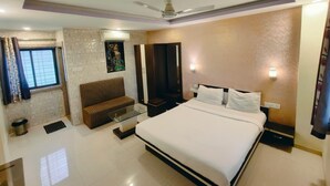 Una habitación de hotel moderna con una cama grande, un sofá, un ventilador de techo y una mesita.
