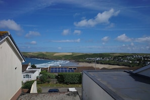 A coastal view with a beach, ocean, and residential area. - Badgers Cliff (Wadebridge)
