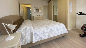 Ein Schlafzimmer mit Bett, Nachttisch, Lampe, Kleiderschrank und Spiegel.