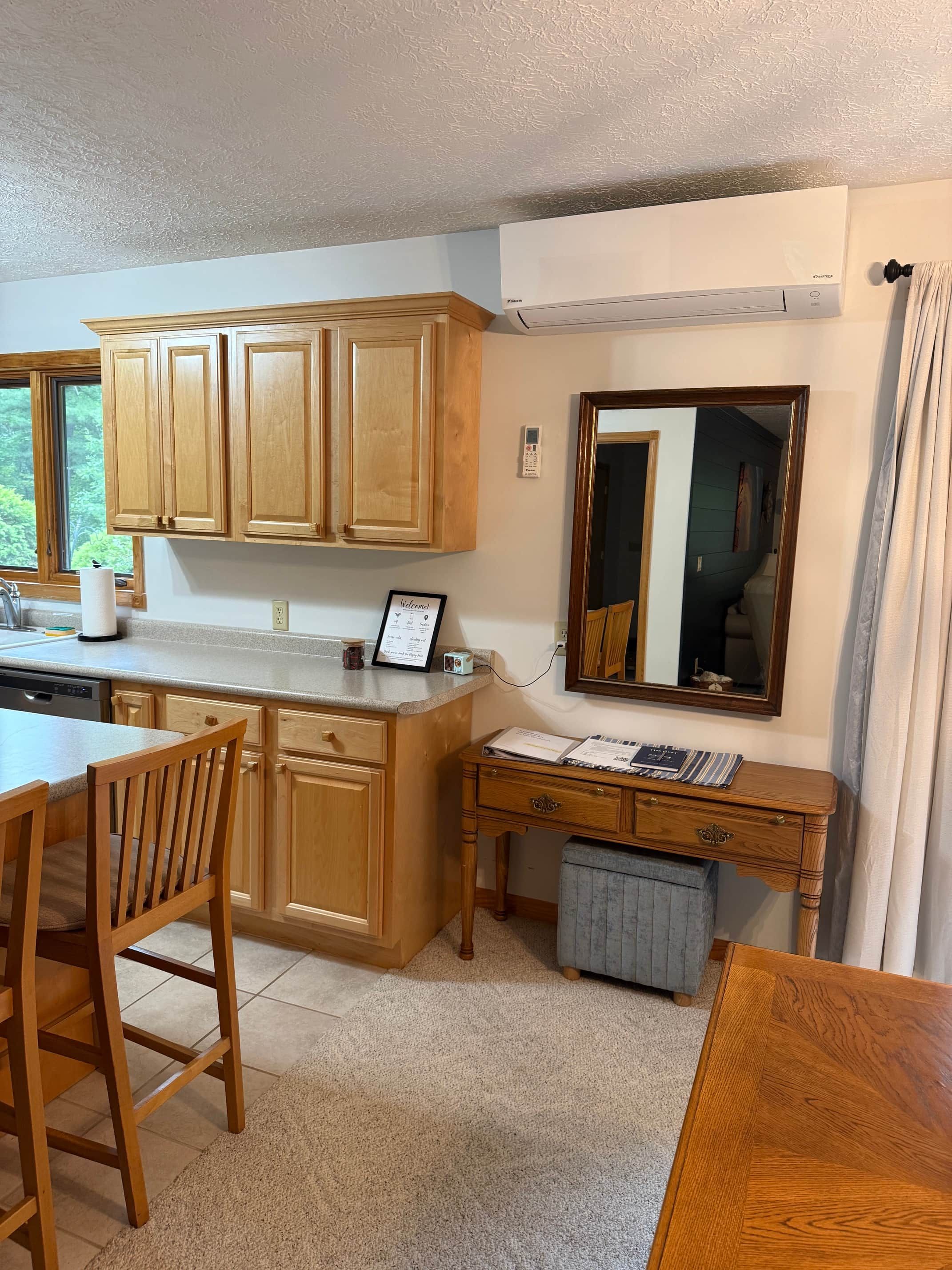 A kitchen with wooden cabinets, a dining table, and a small desk with a mirror.