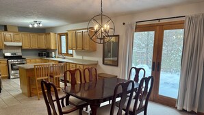 A kitchen with wooden cabinets, a central island, and a dining area with a dark wooden table and chairs. - The Nest, a spacious, secluded pet-friendly retreat! (Barnes)