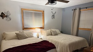A bedroom with two beds, a ceiling fan, a window with blinds, and decorative wall art. - The Nest, a spacious, secluded pet-friendly retreat! (Barnes)