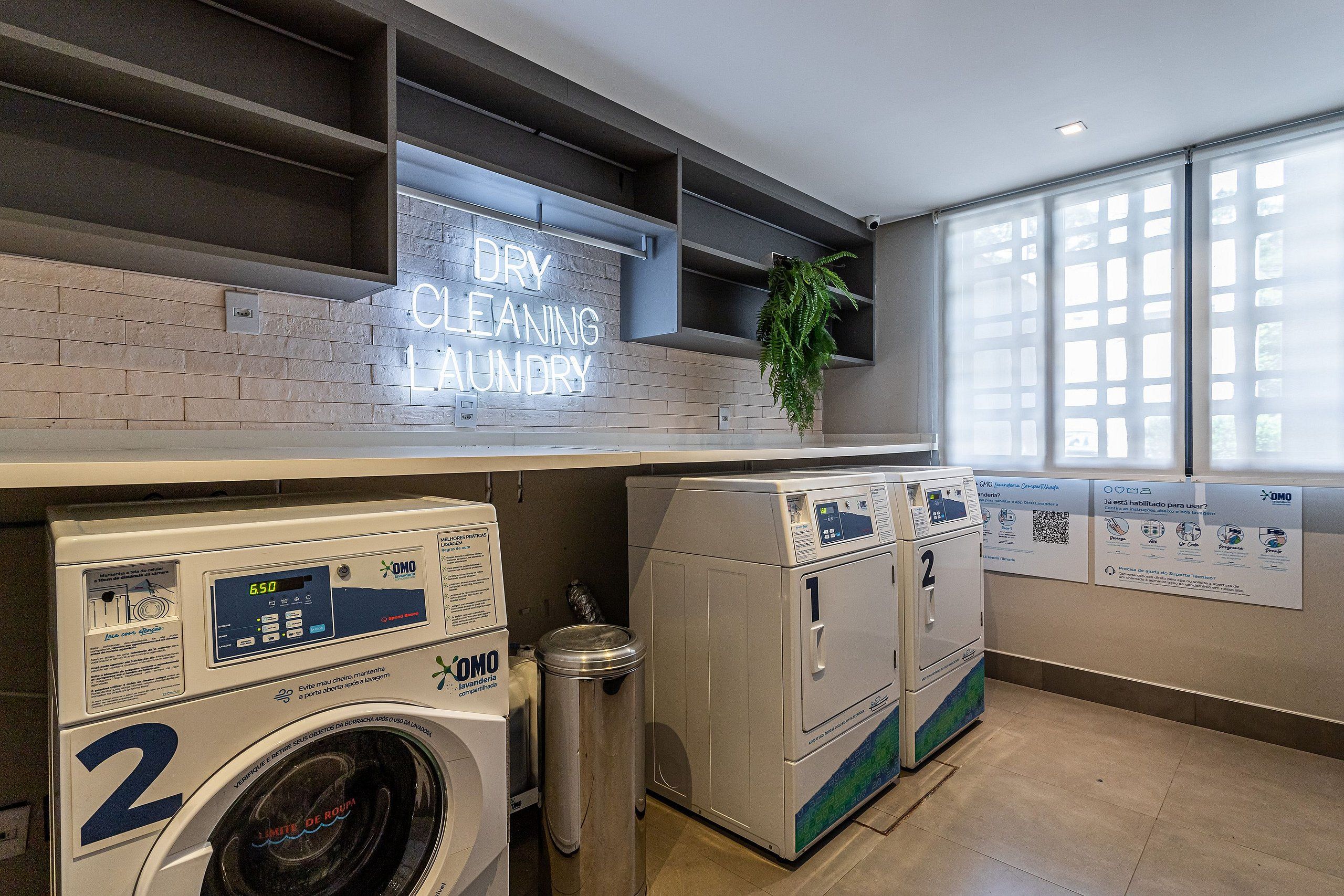 A laundry facility with a neon sign, multiple washing machines, and a trash bin.
