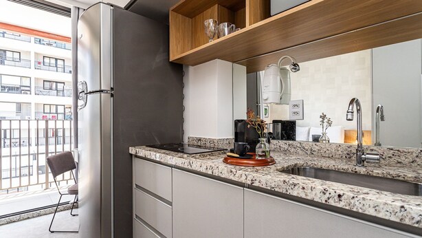 A modern kitchen with a stainless steel refrigerator, granite countertop, and a built-in oven. - Urbic Vila Mariana by Viva - Prédio com academia e coworking a passos da ESPM, Belas Artes e Metrô (São Paulo)
