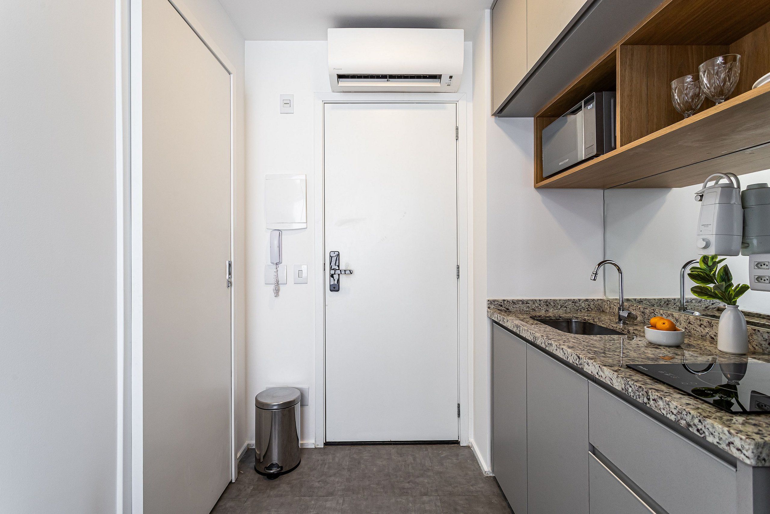 A narrow kitchen with a built-in microwave, a sink, and a small trash bin.