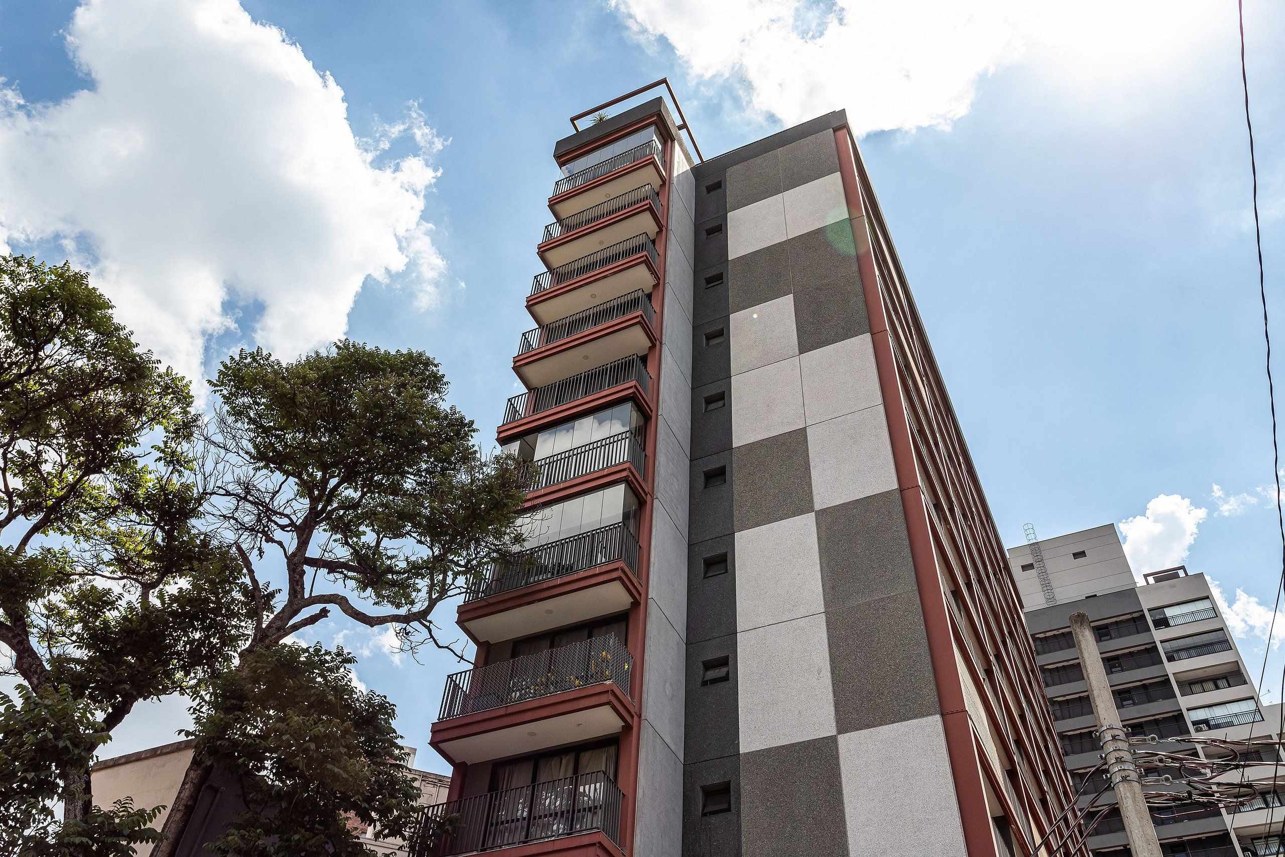 A multi-story building with balconies, a checkered facade, and a clear sky.