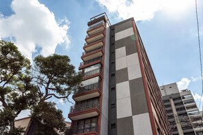Un edificio de varios pisos con balcones, fachada a cuadros y cielo despejado.