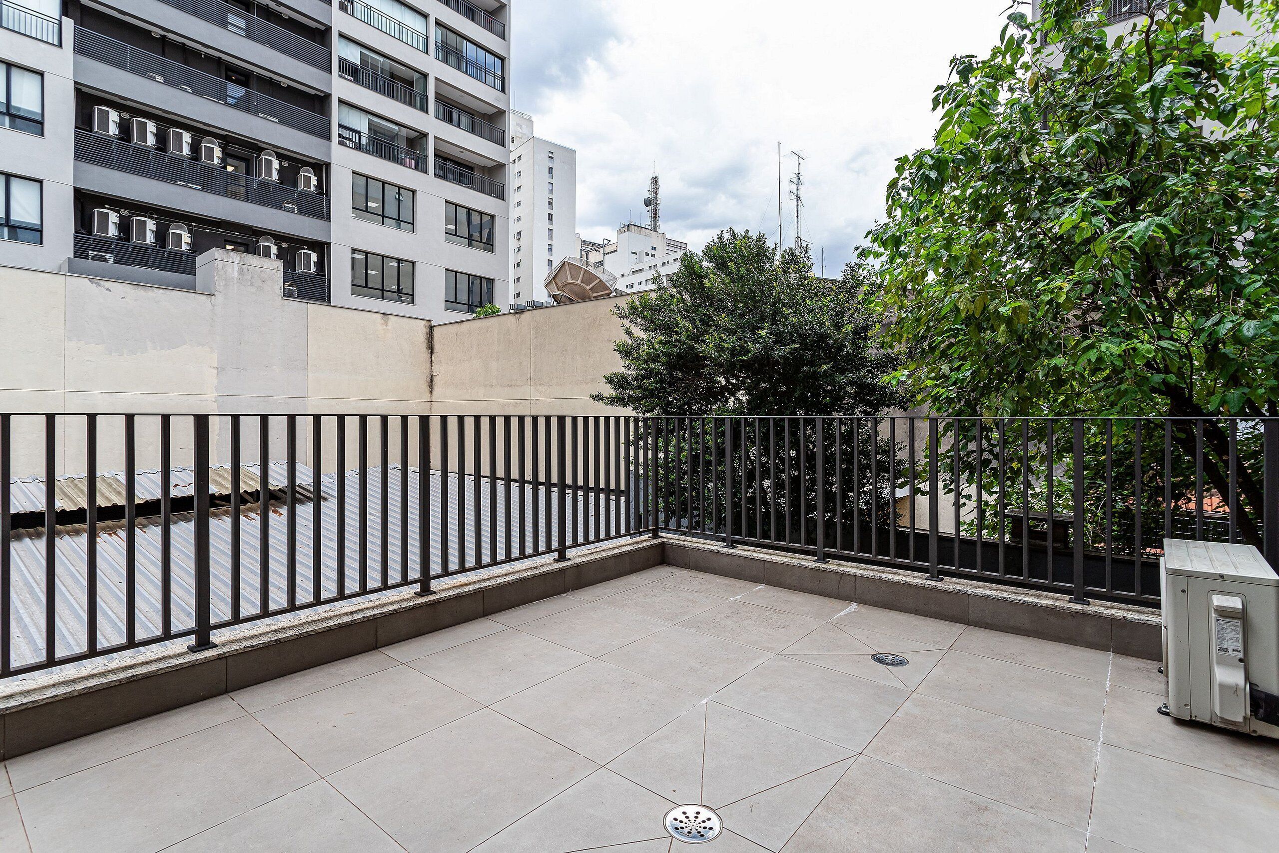 A rooftop terrace with a metal fence, a drainage grate, and a utility box.