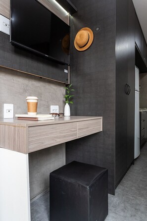Una cocina moderna con horno empotrado, una taza de café, un florero con una planta y un otomano negro.