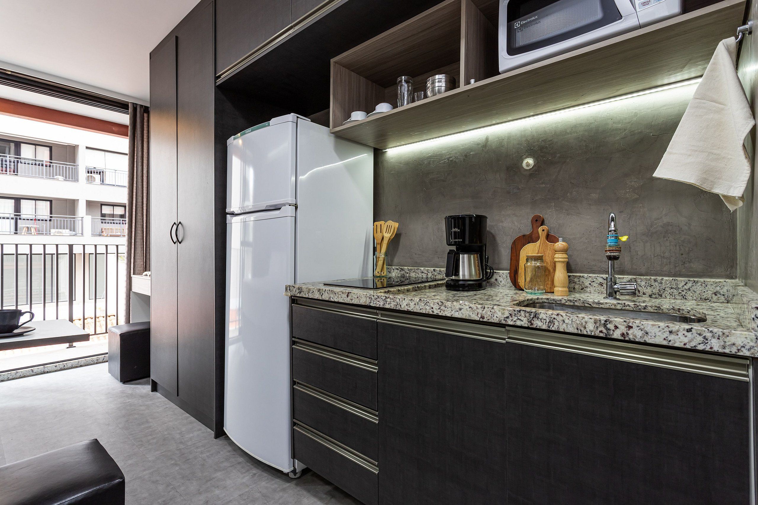 A compact kitchenette with a refrigerator, microwave, coffee maker, and a sink.