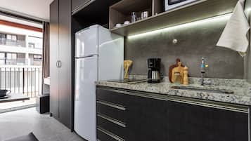 A compact kitchenette with a refrigerator, microwave, coffee maker, and a sink.
