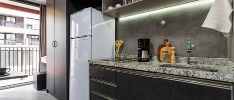 A compact kitchenette with a refrigerator, microwave, coffee maker, and a sink.