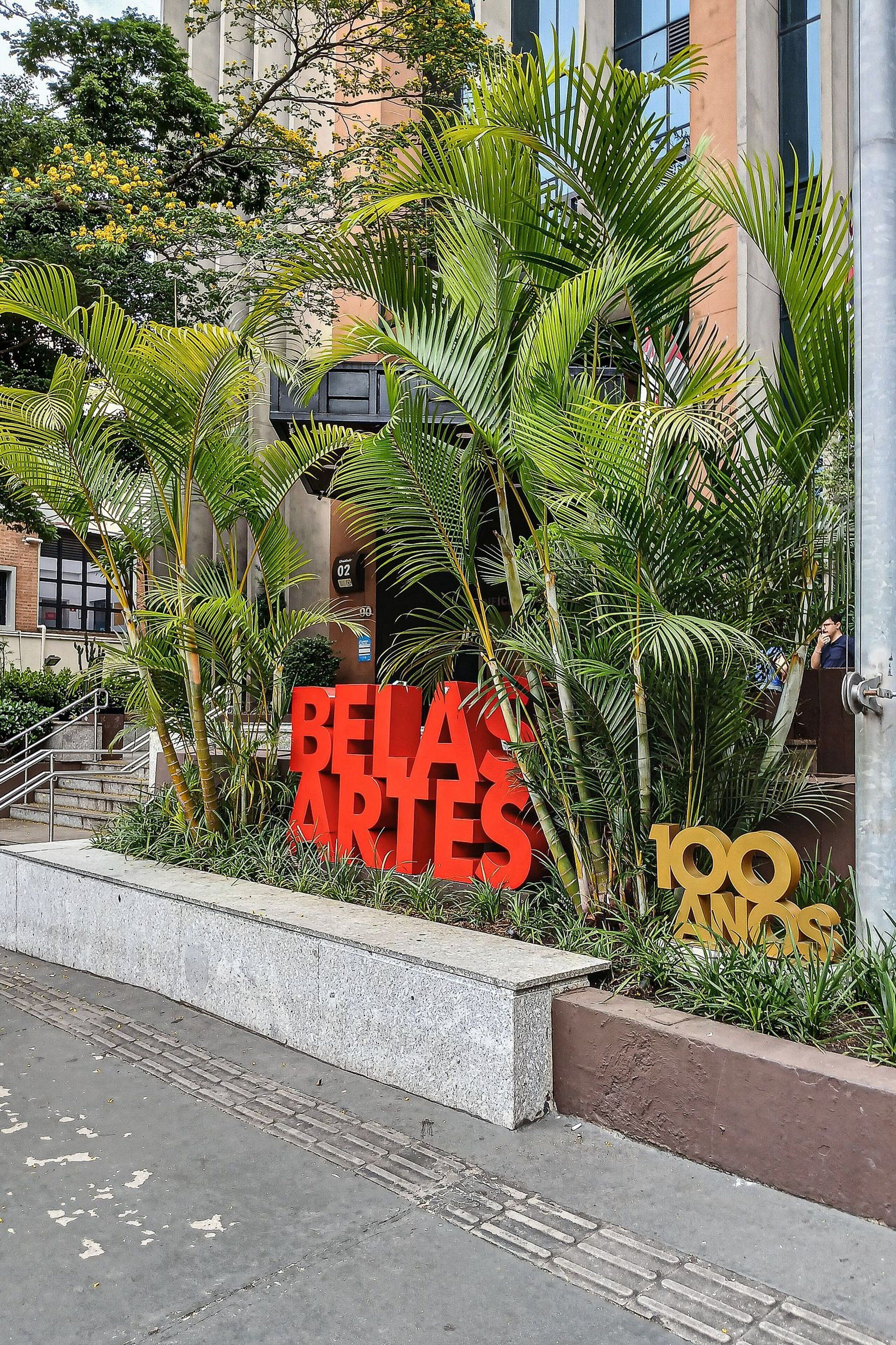 Ein Gebäudeeingang mit einem Schild, auf dem 'BELLA ARTES' und '100 ANOS' steht.
