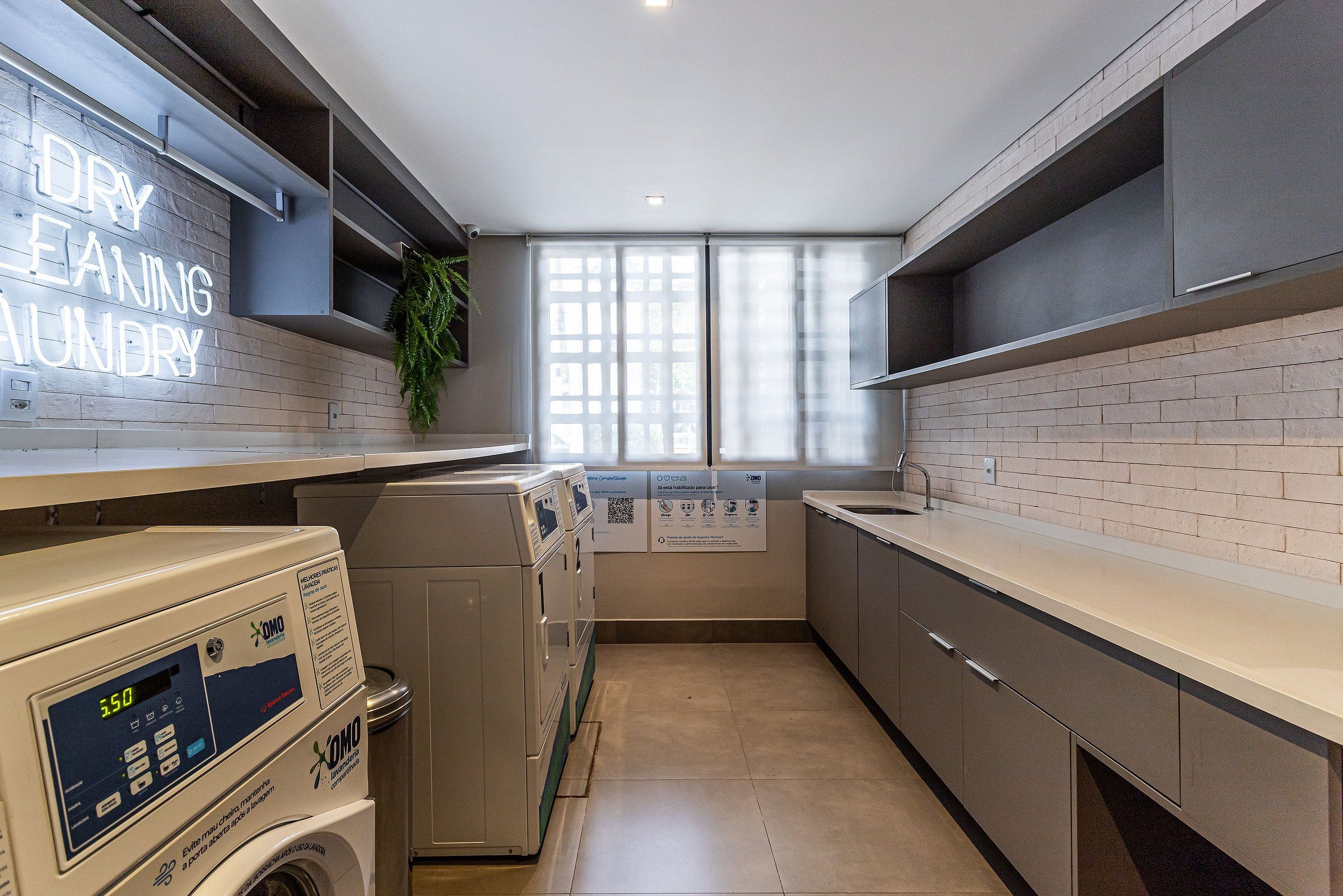 A laundry area with a washing machine, dryer, and a sign that reads 'DRY CLEANING LUNDRY.'