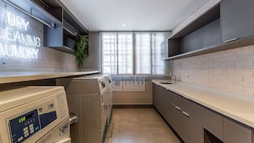 A laundry area with a washing machine, dryer, and a sign that reads 'DRY CLEANING LUNDRY.'