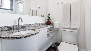 A bathroom with a white sink, a mirror, a shower, and a toilet. - Urbic Vila Mariana by Viva - Prédio com academia e coworking a passos da ESPM, Belas Artes e Metrô (São Paulo)