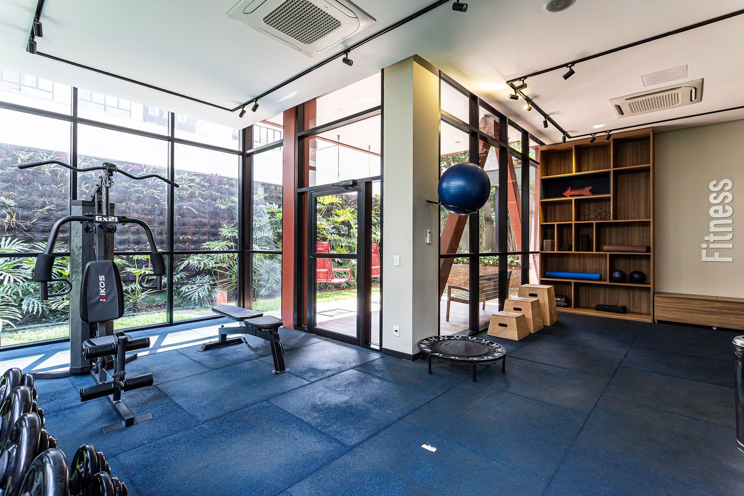 A gym with exercise equipment, a large window, and a view of greenery.