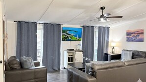 Un saló modern amb un sofà, una taula de centre, una televisió i un ventilador de sostre.