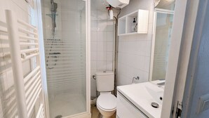 Een moderne badkamer met een douche met glazen wand, een toilet en een wastafel met spiegel erboven.