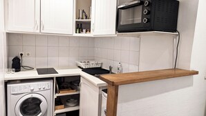 Een kleine keuken met een wasmachine, een magnetron en een klein aanrecht.