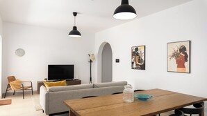 En moderne stue med sofa, træspisebord og hængende sorte lamper.