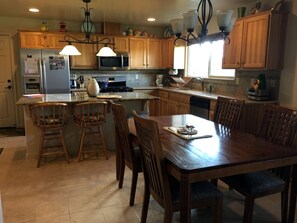 A kitchen with wooden cabinets, a dining table, bar stools, and a stove.
