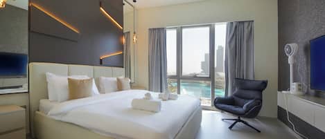 A modern hotel room with a large bed, a flat-screen TV, a desk, and a view of the city.