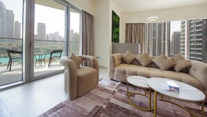 A modern living room with a sofa, armchair, and coffee table, large windows with a city view, and a balcony with outdoor furniture. - 3BHK Sea View Near Palm Jumeirah Avani  (Dubai)
