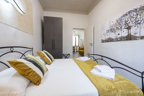 A hotel room with a bed, a wardrobe, a painting, and a view into another room. - Cozy apartment in the historic center of Siena, located in the Contrada del Leocorno.It can accommodate up to 6 guests with two double bedrooms and a room with a bunk bed and desk. Equipped with a fully equipped kitchen, Wi-Fi, TV, washing machine, linen (Siena)