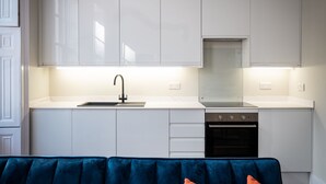 A modern kitchen with white cabinets, a black faucet, and a built-in oven. - Dalton Sq Apartments (Lancaster)